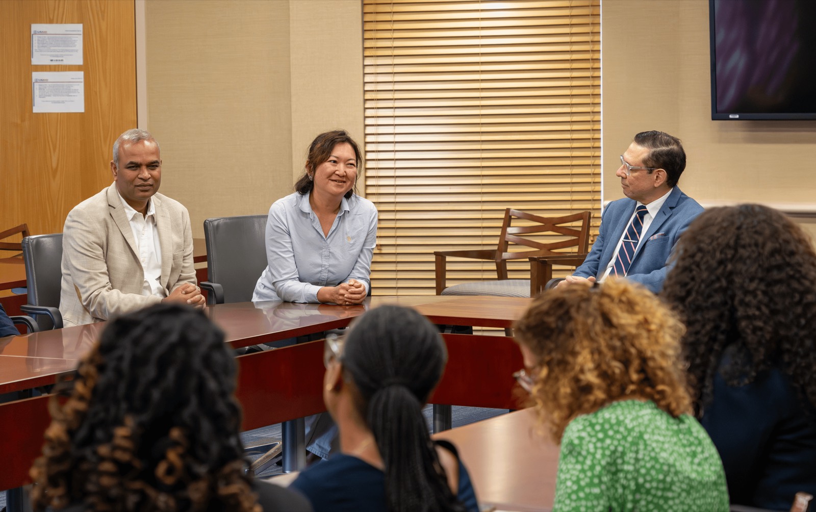 A panel of three speakers in discussion with participants around a boardroom table