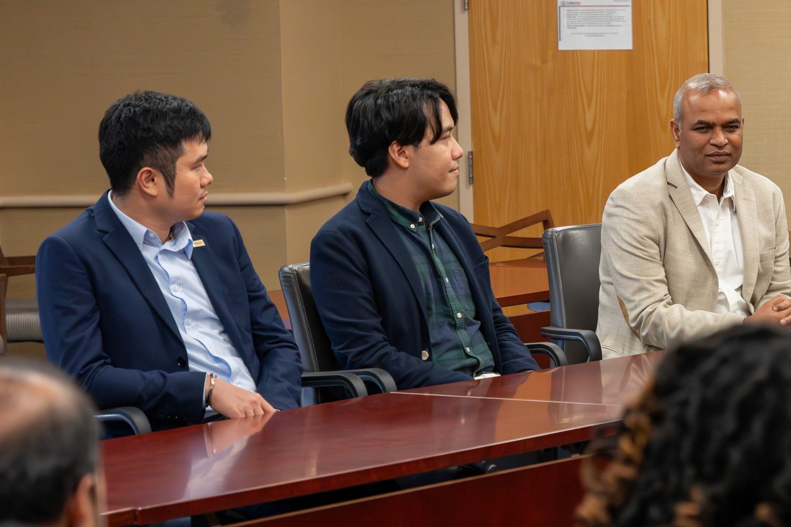 Three participants seated at a boardroom table during a group session